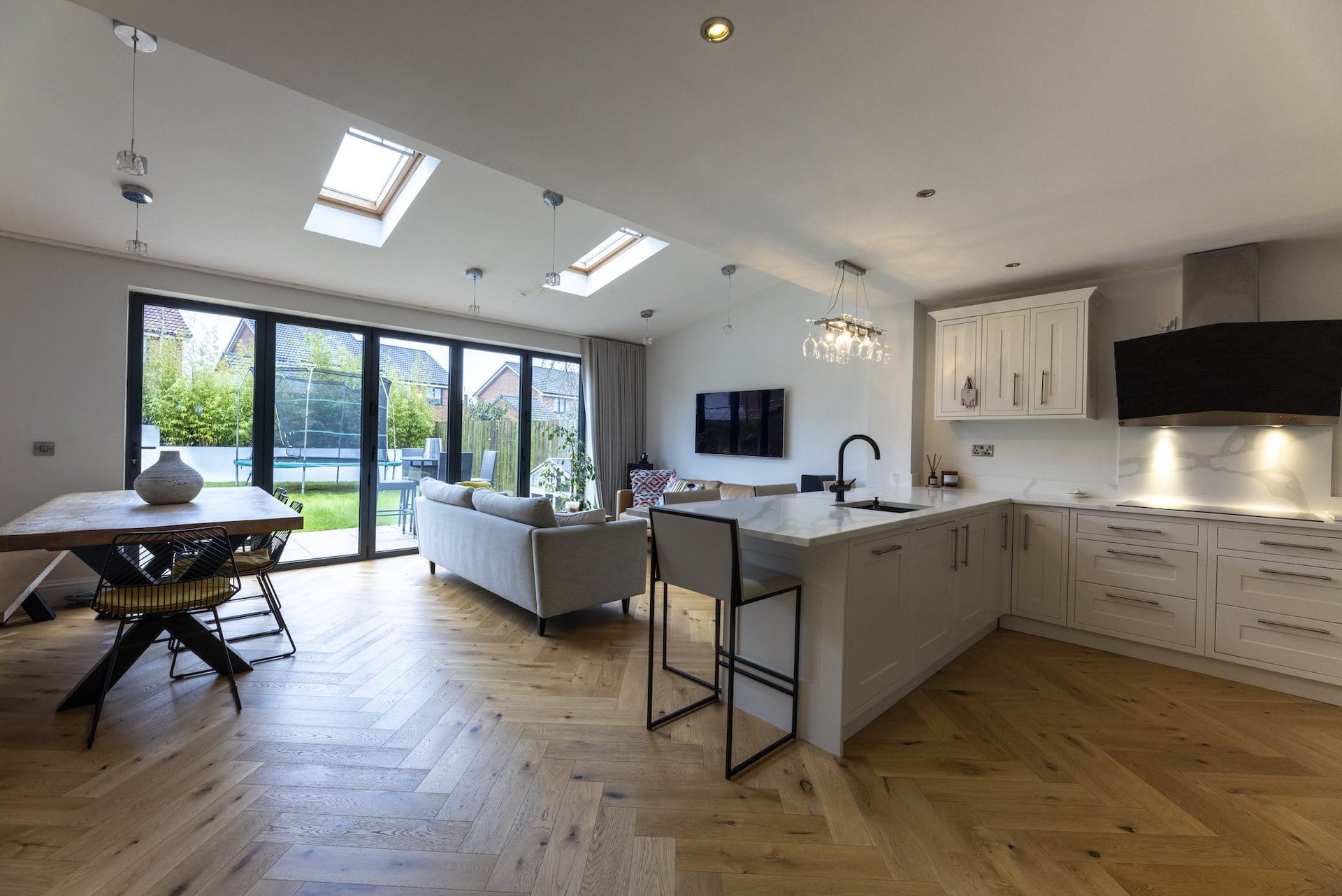 Open plan kitchen and living space with herringbone oak flooring and bi-fold doors